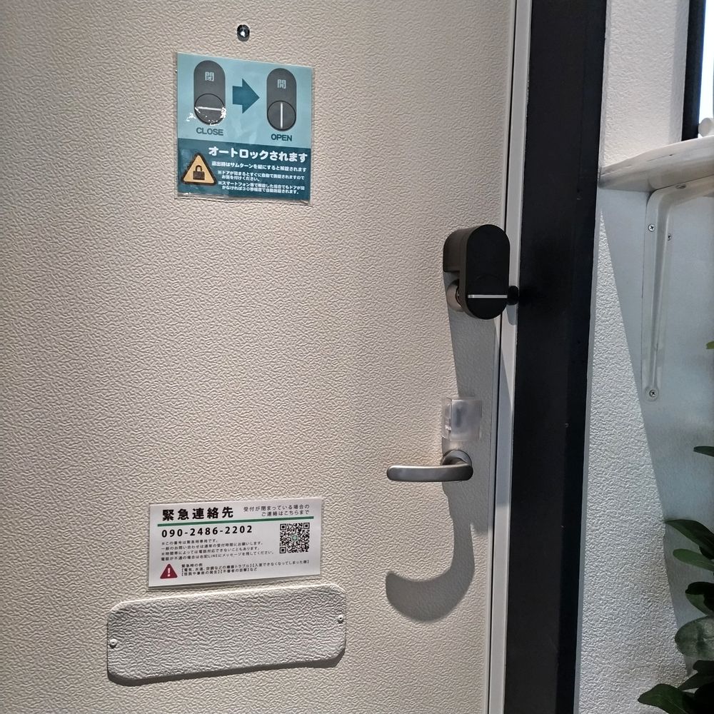 入り口ドアの内側。オートロックの案内と緊急連絡先の掲示