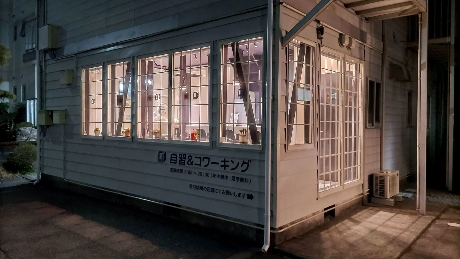 夜の外観。自習＆コワーキングのサインが灯る